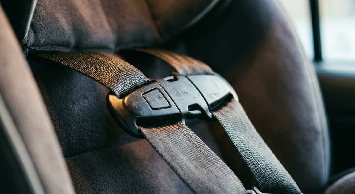 A chest clip fastened across a car seat harness, tight close-up
