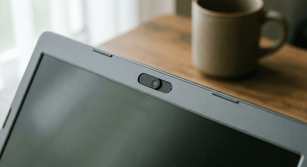 Close-up of a small webcam cover slider on the top bezel of a grey laptop