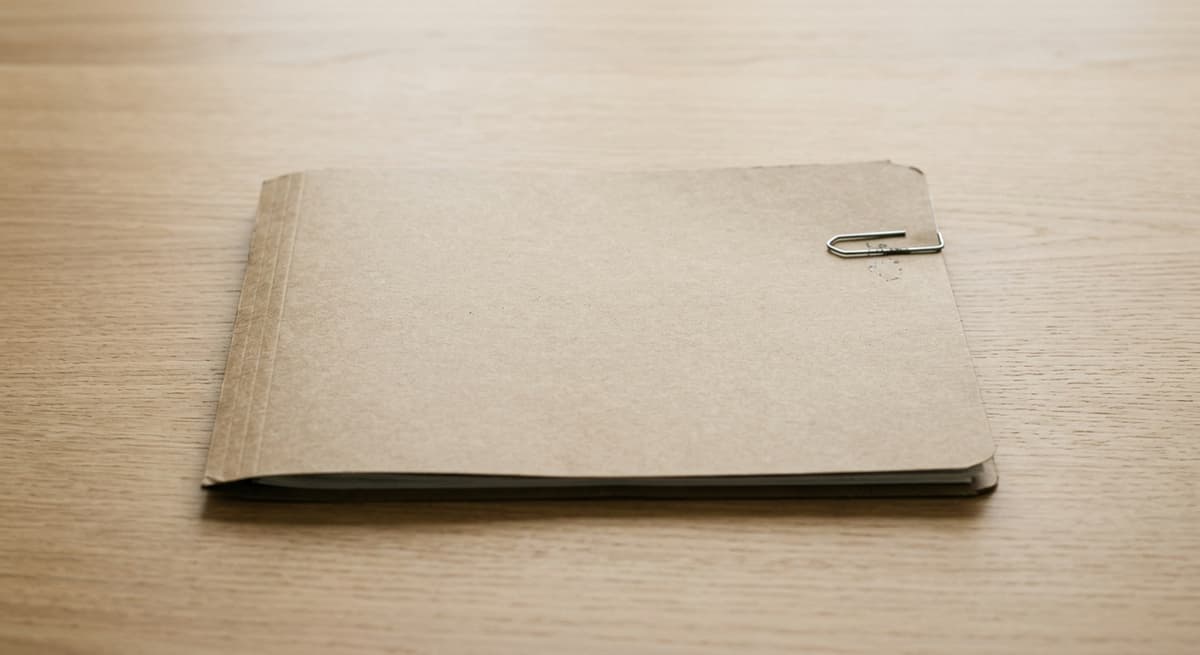 World closed file folder with a single paper clip on a clean light wood desk