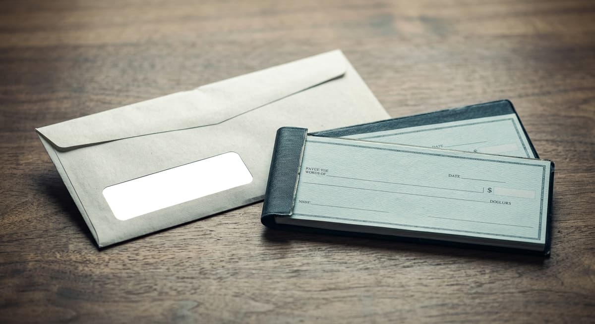 Squatters rights a property tax bill envelope and a checkbook lying on a wooden desk